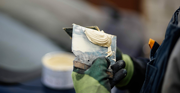 Auto body filler applied to a putty knife during car repair.